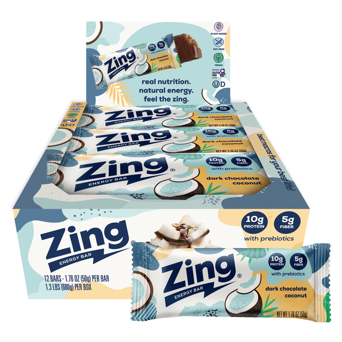 A box of Zing Energy Bar snack sticks with two individual bars displayed in front on a plain white background. The packaging features light blue, white, and yellow graphics with coconut illustrations and text indicating dark chocolate coconut flavor and prebiotics.