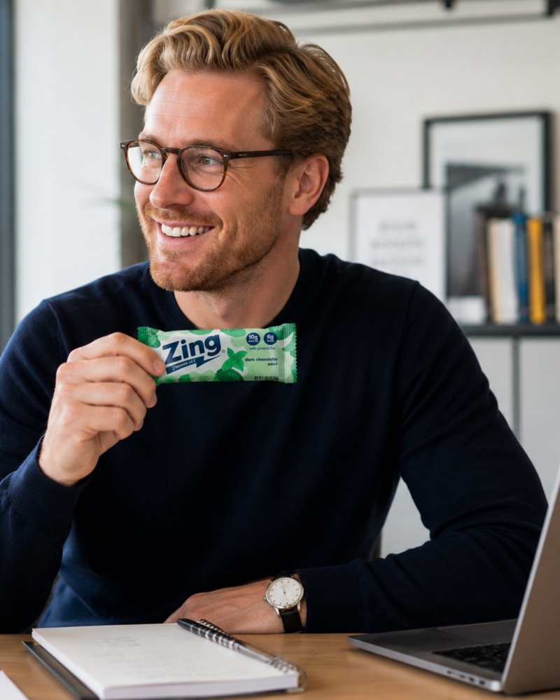 professional holding a dark chocolate mint zing energy bar while working at a desk