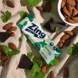Zing energy bar with dark chocolate and mint on a light background with almonds and mint leaves.