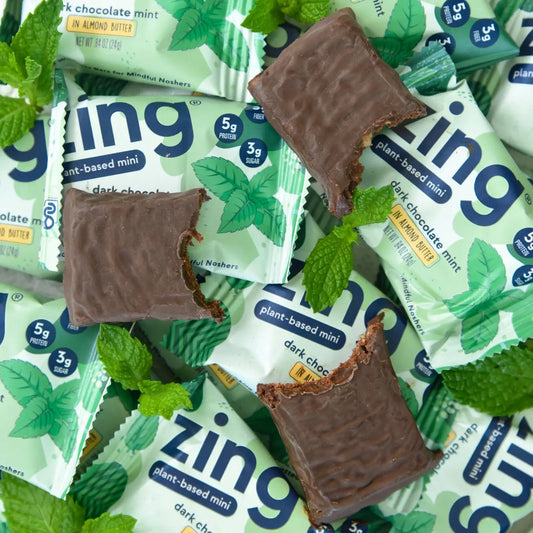 pile of dark chocolate mint mini bars with mint leaves and three bars with bites taken out of them