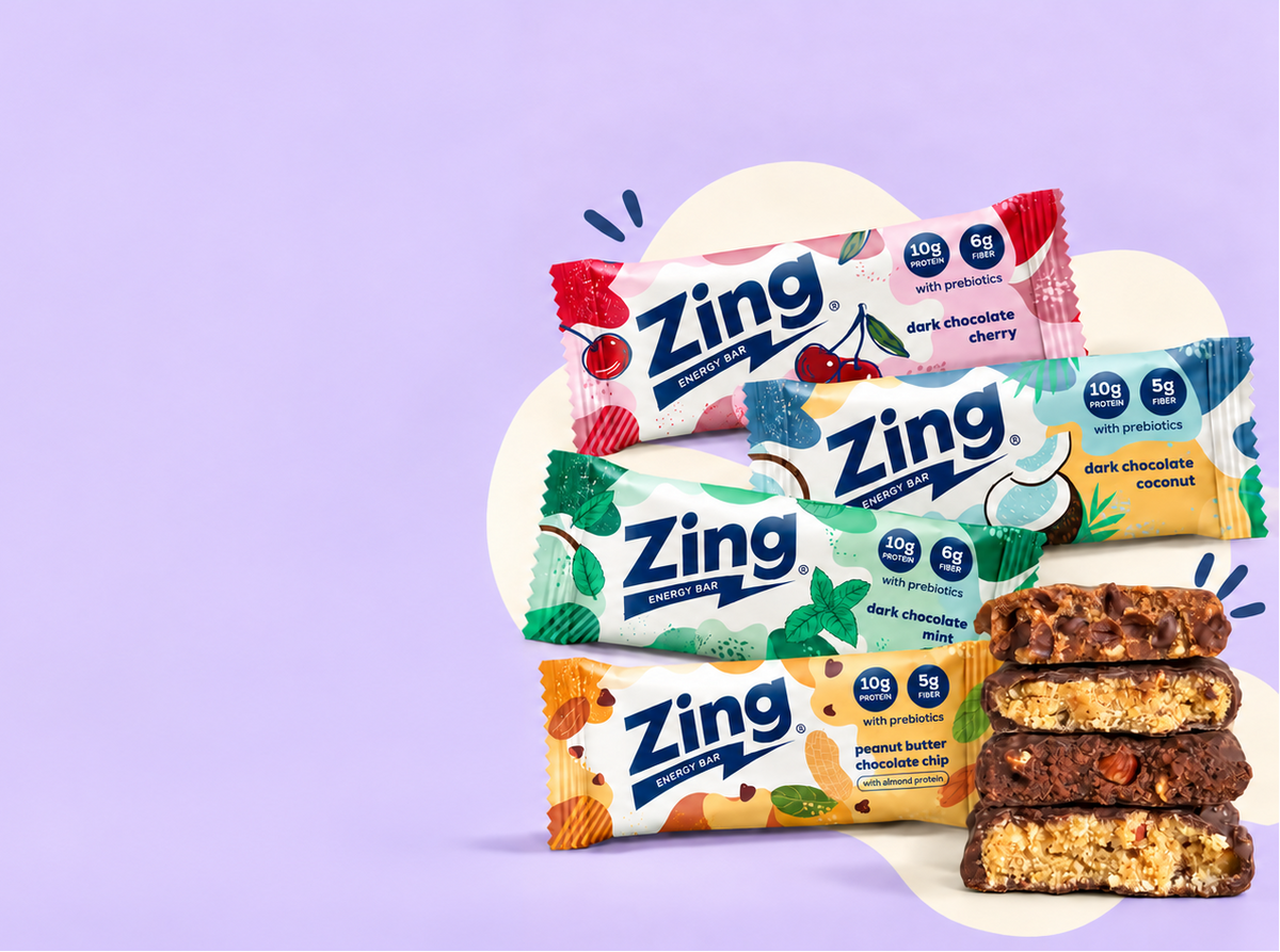 Four wrapped Zing bars in cherry, coconut, mint and peanut butter chocolate chip flavors beside stacked bar halves on a lavender background.