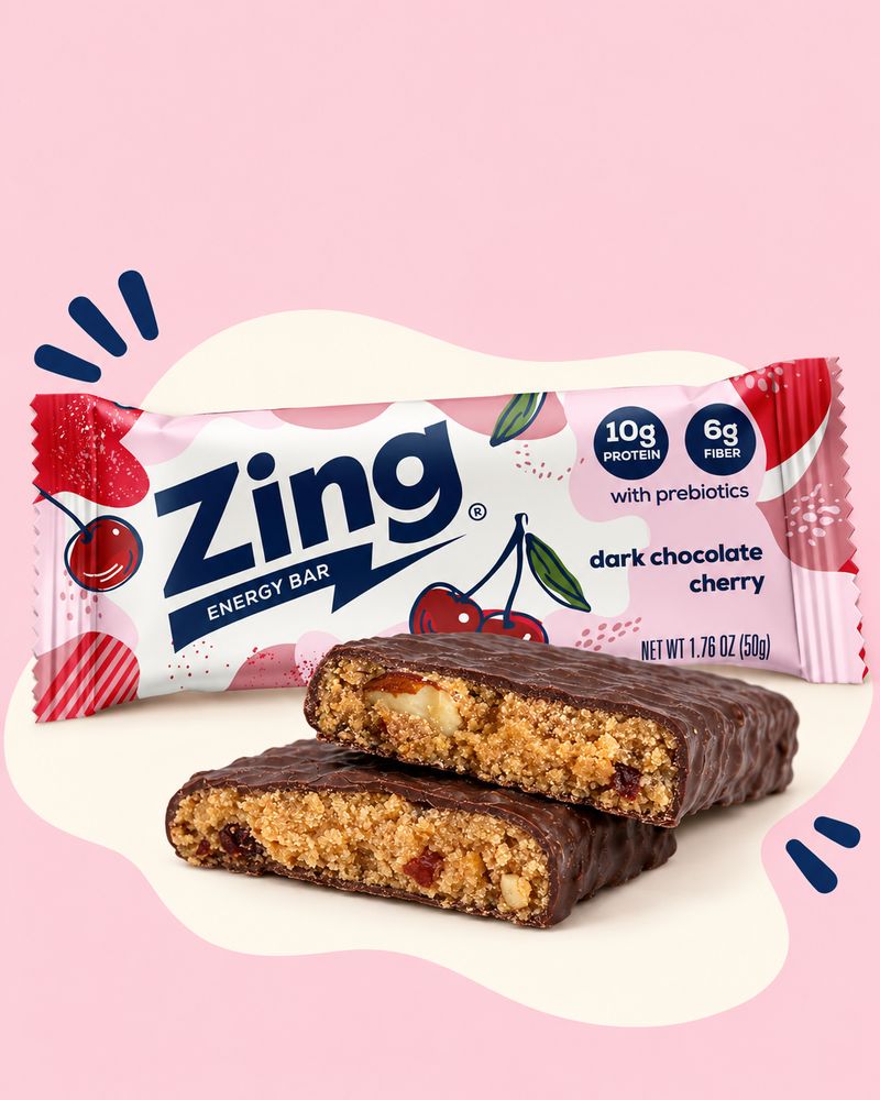 Wrapped Zing Dark Chocolate Cherry bar behind two stacked bar halves showing cherries and almonds inside.